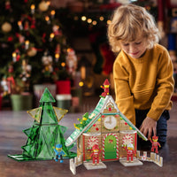 Young child playing on the floor with a Christmas-themed magnetic tile house, tree, and figures.   