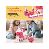 Two girls building a pink Hello Kitty magnetic tile castle on a carpet below a promotional banner.