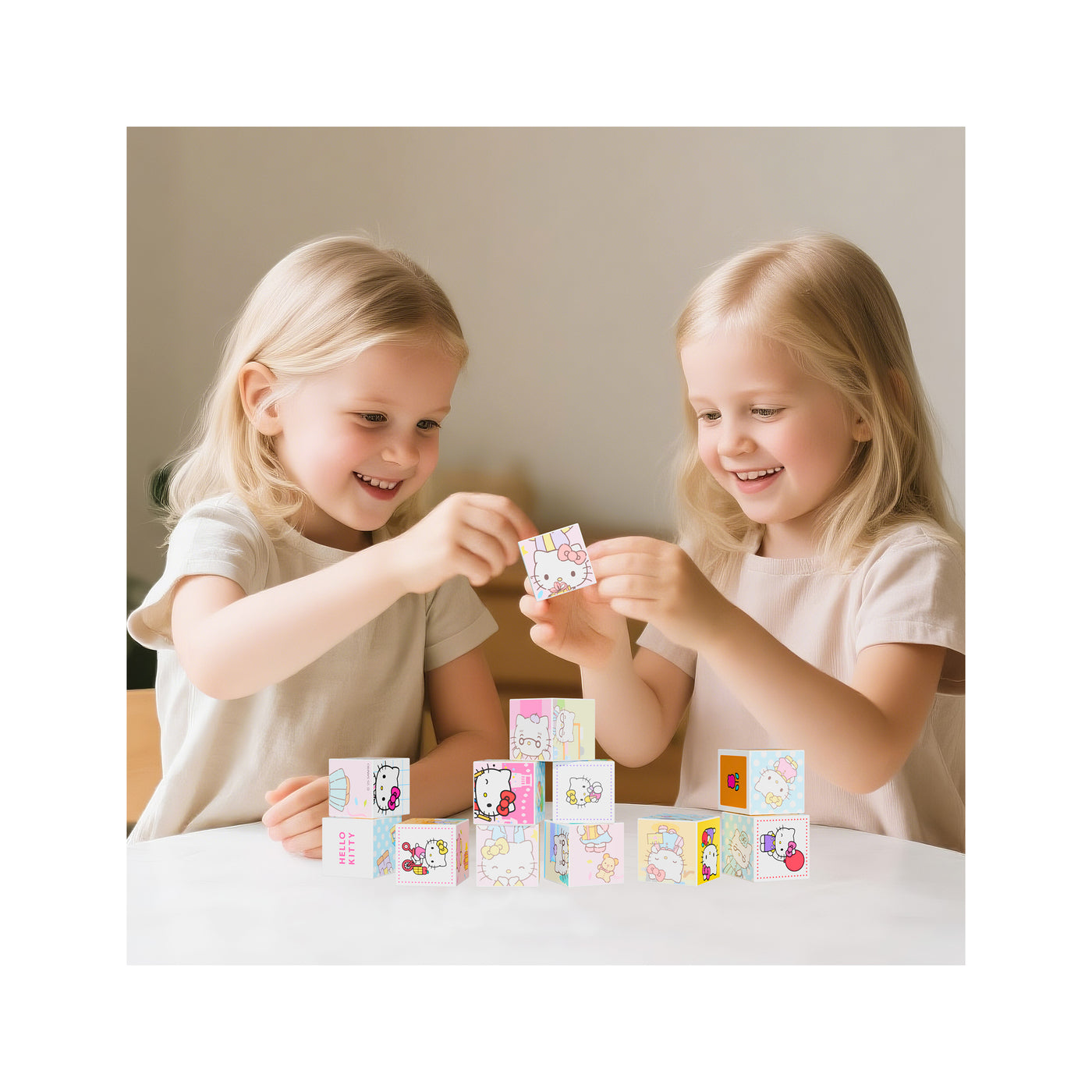 Two girls playing together at a table, stacking pink and blue Hello Kitty magnetic blocks.