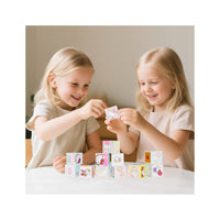 Two girls playing together at a table, stacking pink and blue Hello Kitty magnetic blocks.