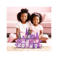 Two smiling girls with a purple and pink Kuromi magnetic tile castle on a playroom floor.