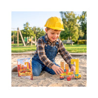 Child in hard hat playing with PicassoTiles magnetic construction blocks and tin case in sand.