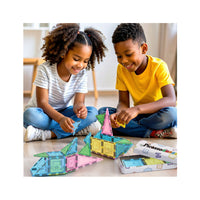 Two smiling children playing with colorful, translucent tiles on the floor next to an open storage tin.