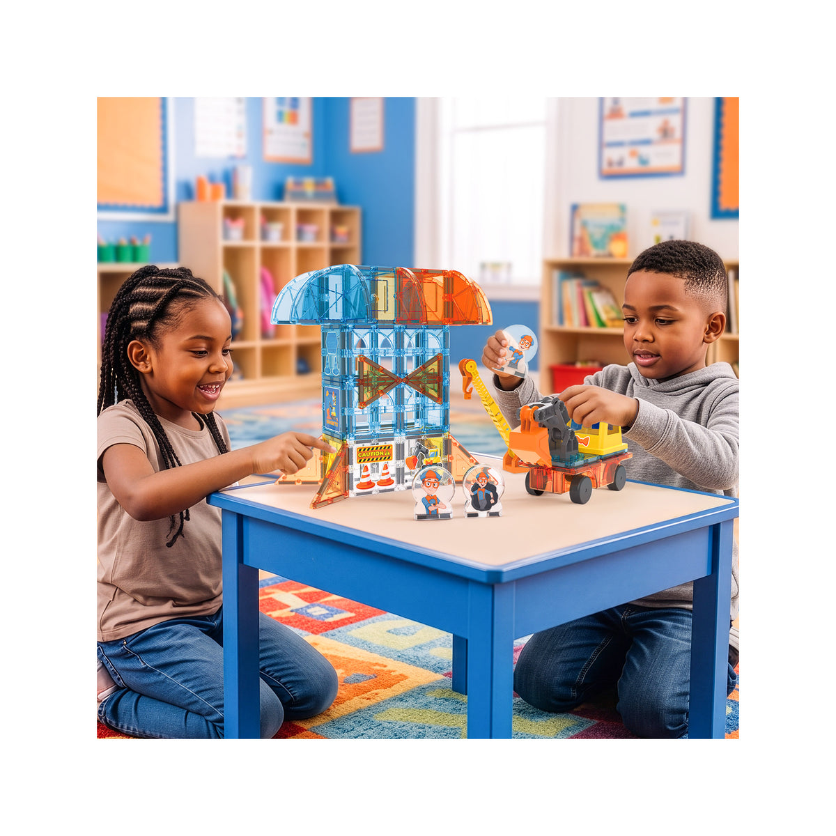 Two children playing at a table with colorful magnetic building tiles, constructing a tower and playing with a toy construction vehicle.