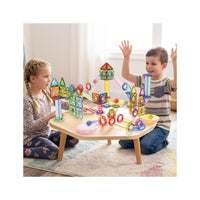 Two children playing with an assembled PicassoTiles magnetic marble run playset on a wooden activity table.