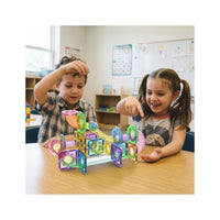 Two kids playing with an assembled PicassoTiles magnetic marble run track at a classroom table.