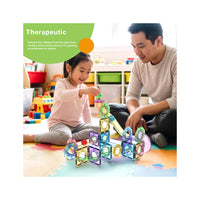 Father and daughter building a magnetic marble run on a play mat with a green "Therapeutic" banner.