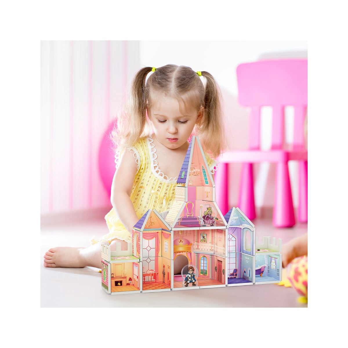 Little girl sitting on the floor playing with a PicassoTiles magnetic princess castle dollhouse.