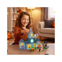 Young girl playing with a Halloween magnetic haunted house set on a table.