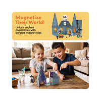 Two kids playing with magnetic house tiles on a wooden table beneath text reading "Magnetize Their World!".