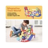 Boy playing with a PicassoTiles magnetic marble run and car track under a Magnetize Their World promotional banner.