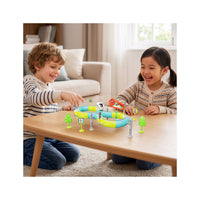 Two children smiling and playing with a toy train set on an elevated figure-8 track with signs and trees.