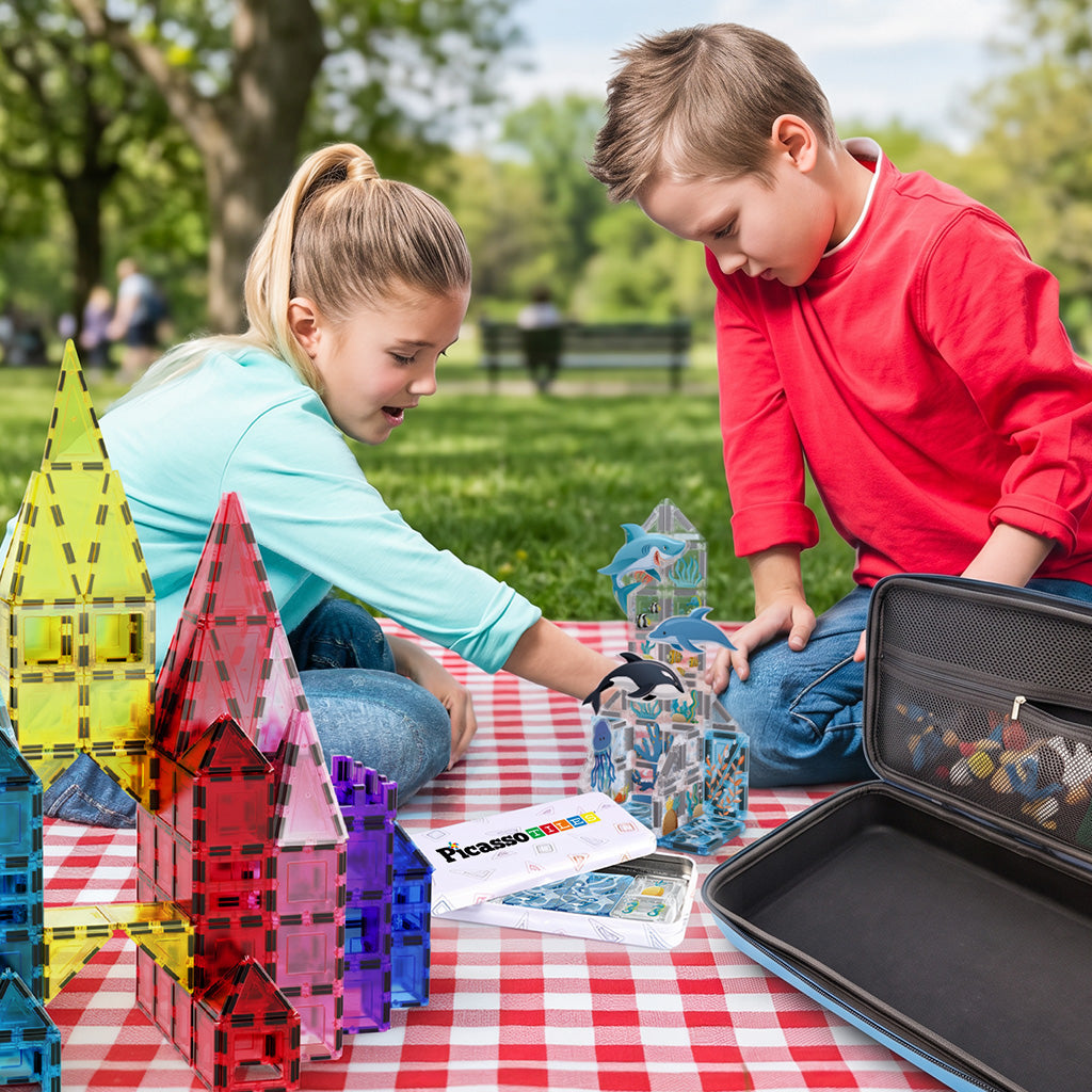 Children playing outdoors with PicassoTiles magnetic tiles, ocean set, and portable storage case.